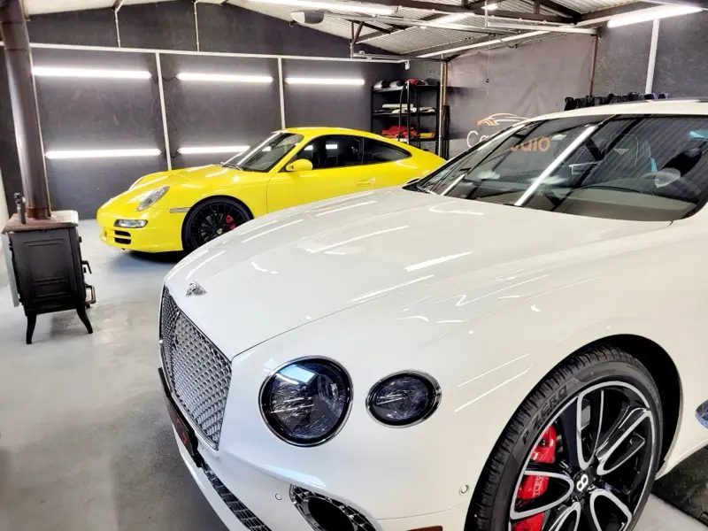Biały Bentley Continental i żółte Porsche 911 w studiu